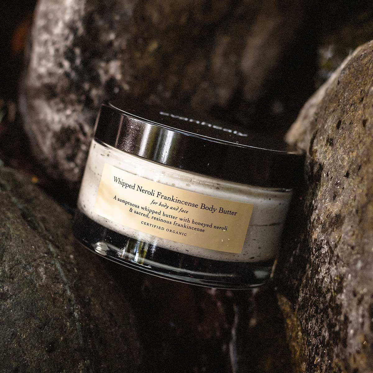 whipped neroli frankincense body butter on rocks of waterfall