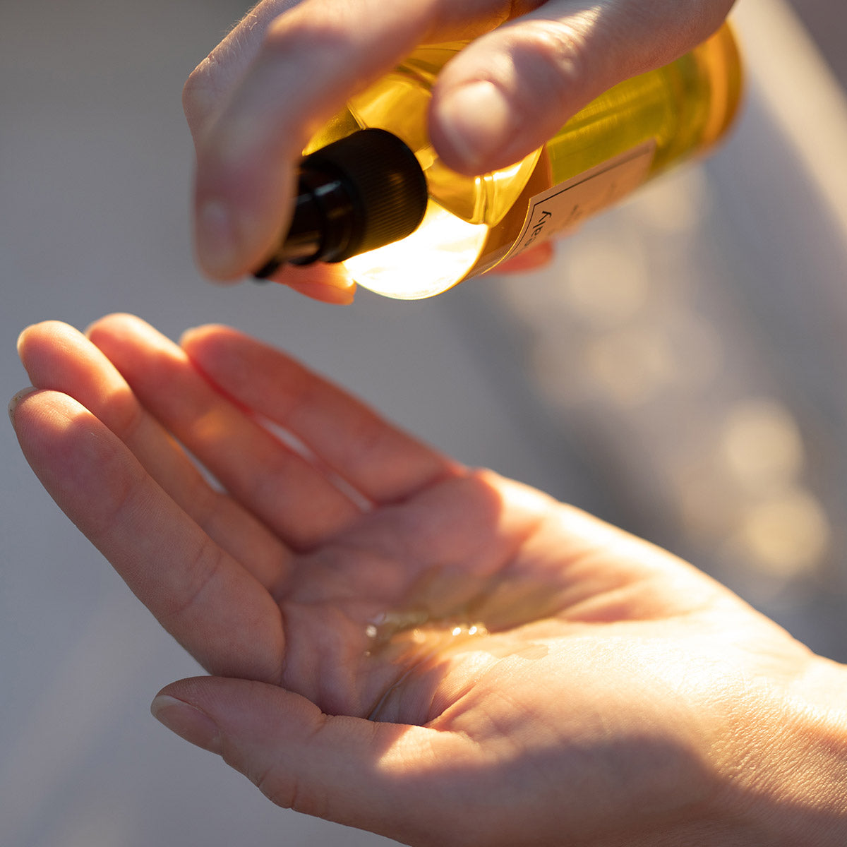 model pumping neroli frankincense body oil in sunlight