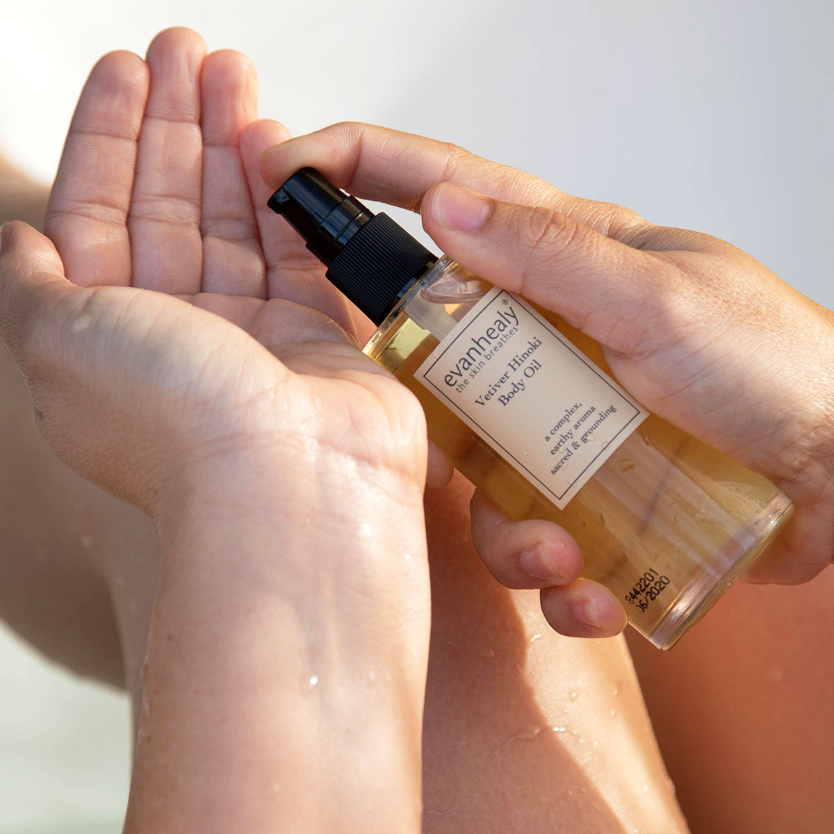 moisturizing body oil being pumped into hand in bath tub to moisturize skin