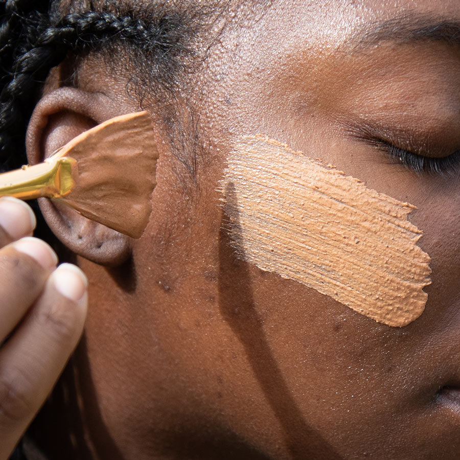 close up of french rose clay mask brushed on cheek with fan brush