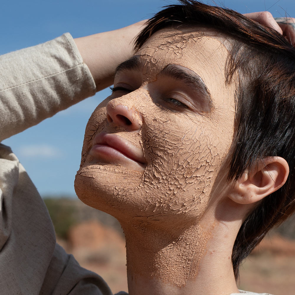 model outdoors with dry clay mask on face