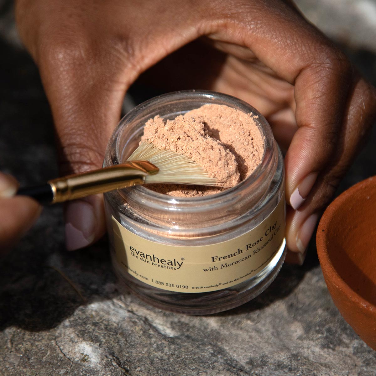 scooping french rose clay for jar with natural boar hair bristle fan mask brush