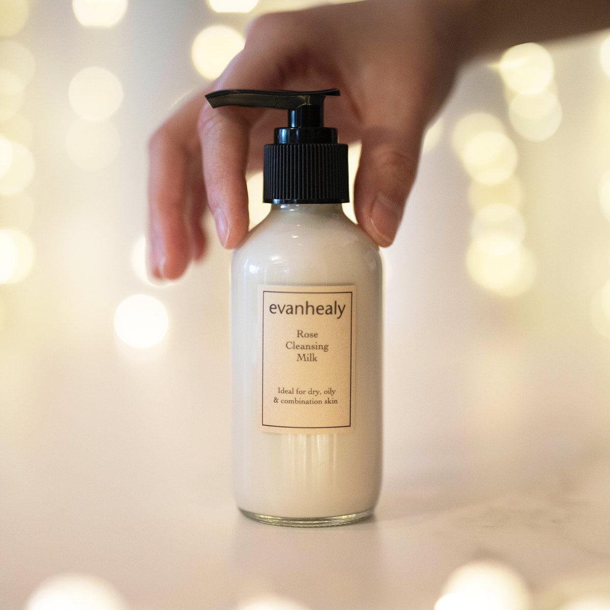 rose cleansing milk cream facial cleanser in fingertips