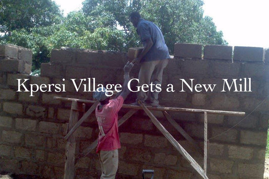 Two men building a brick wall on wooden scaffolding in a village setting