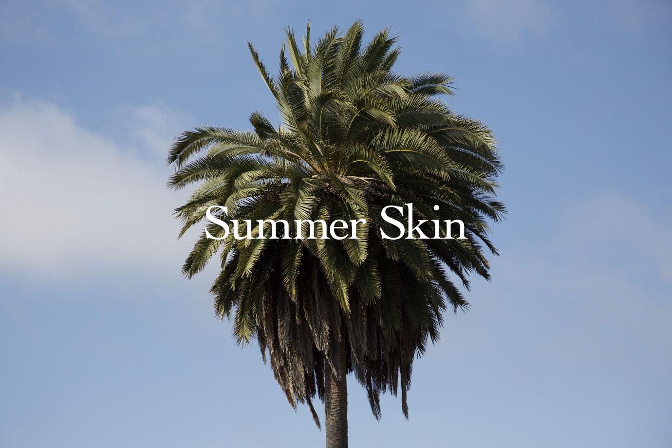 Palm tree standing against a clear blue sky with the overlaid headline Summer Skin