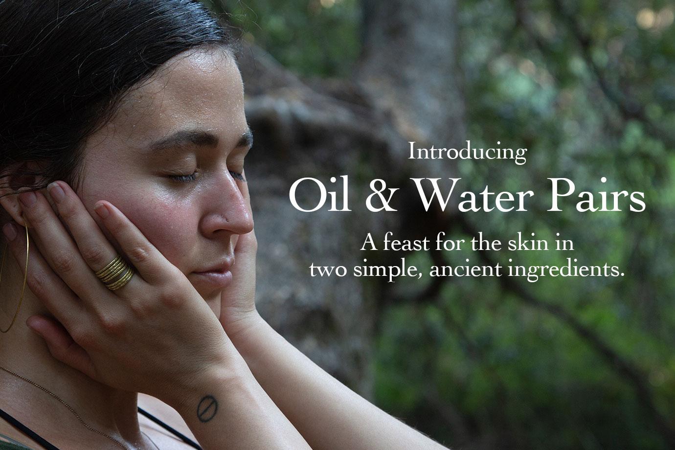 Woman with eyes closed cupping her face in a wooded setting with overlay text Oil & Water Pairs