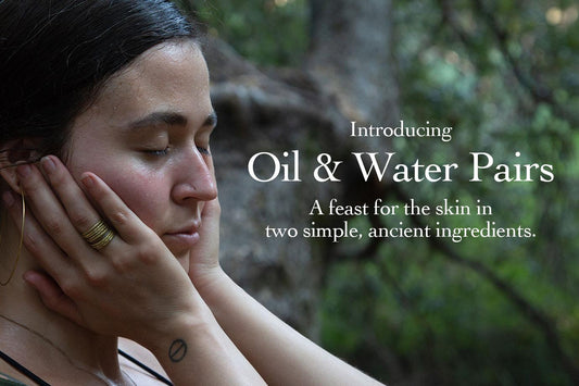 Woman with eyes closed cupping her face in a wooded setting with overlay text Oil & Water Pairs
