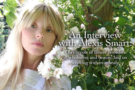 Blonde woman posing among white roses in a sunlit garden