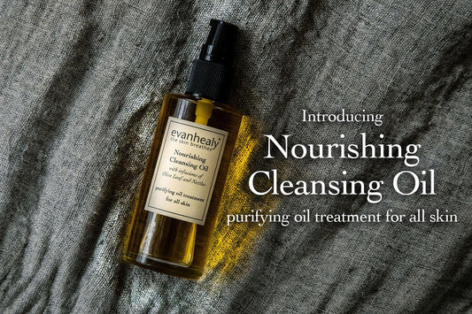 Angled front view of Nourishing Cleansing Oil bottle showcasing amber cleansing oil and pump top with textured gray linen background