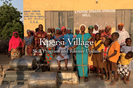 Kperisi village residents posing around metal roasting drums outside a yellow building