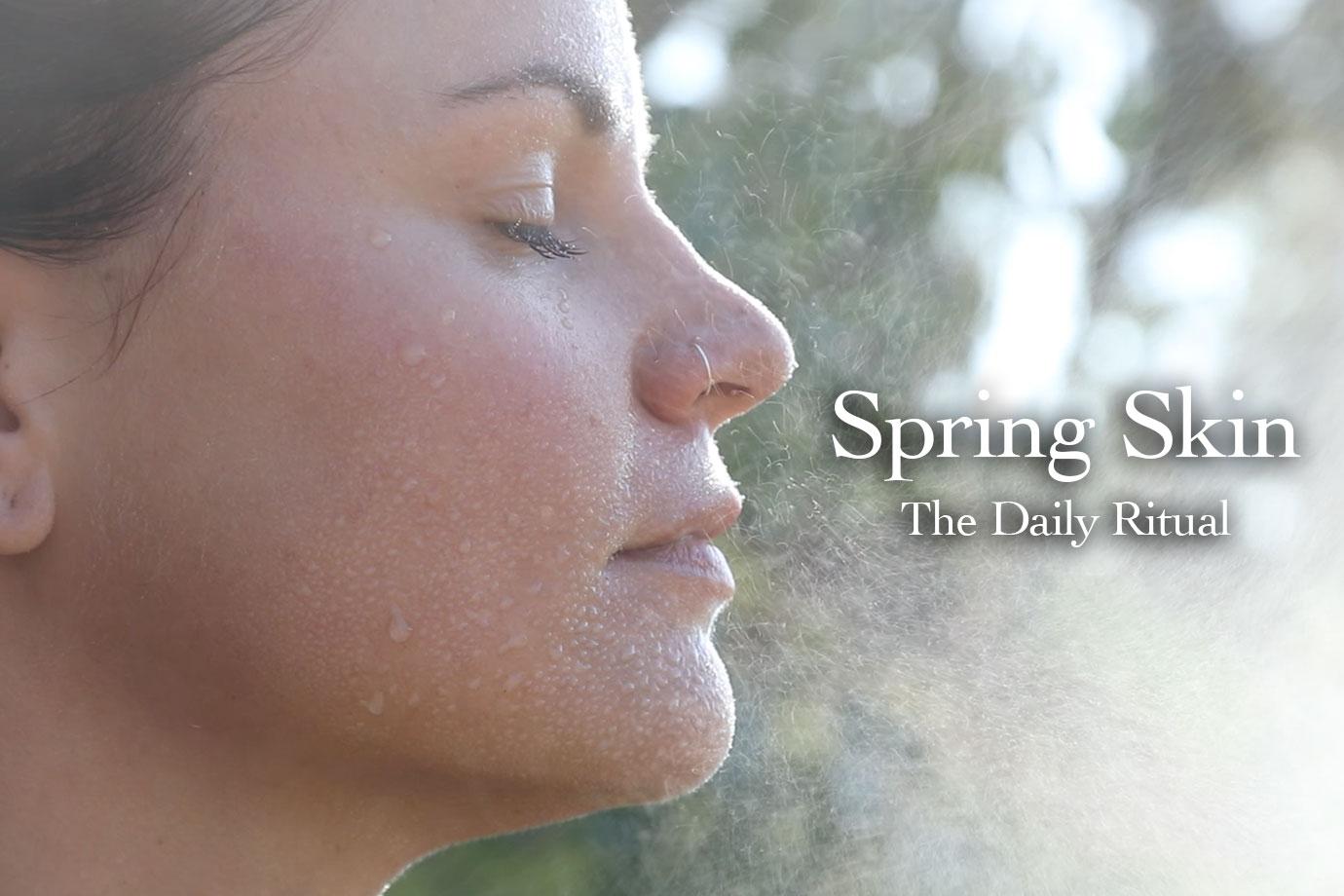 Woman with water mist and droplets on her face, eyes closed outdoors, text overlay ‘Spring Skin The Daily Ritual’