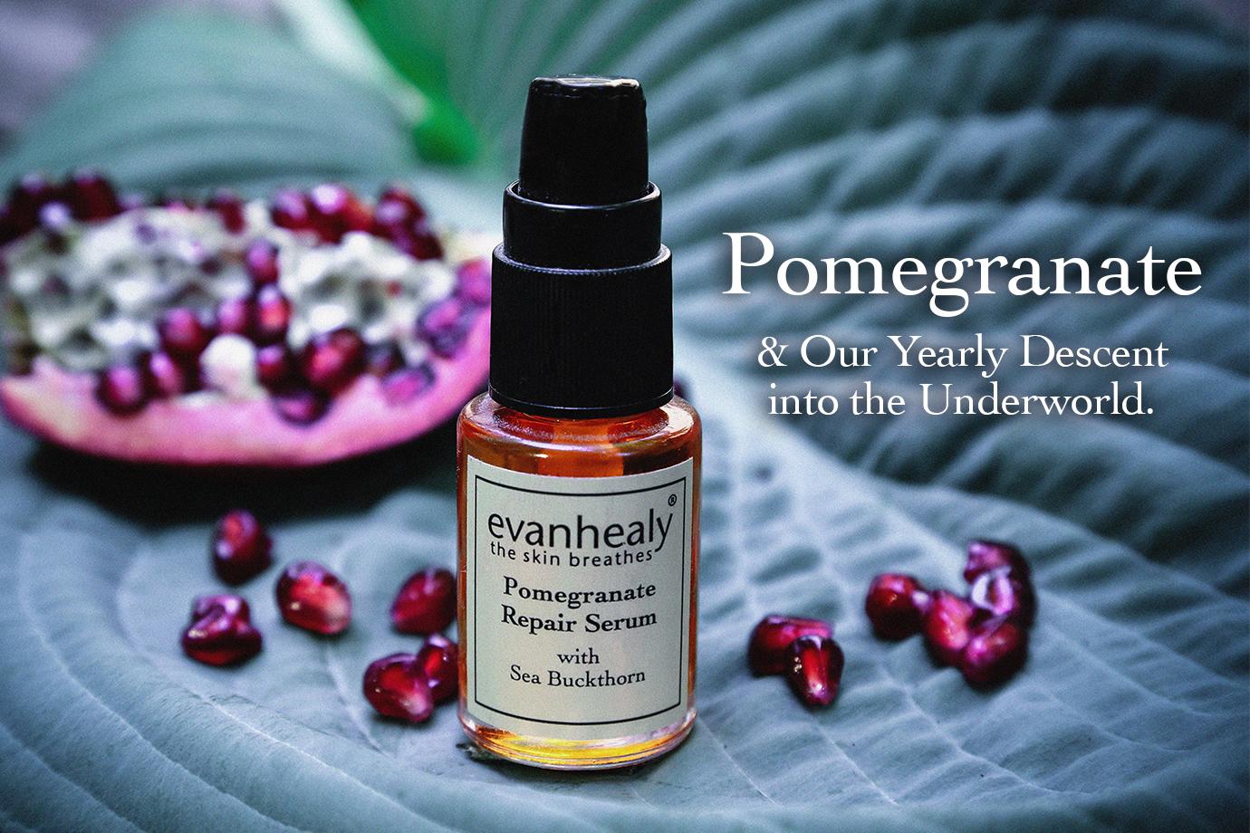 Evan Healy Pomegranate Repair Serum bottle resting on a large leaf with scattered pomegranate seeds