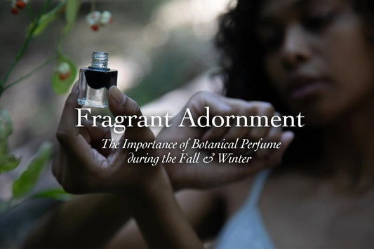Close-up of a person holding a small glass perfume vial near green seed pods, evoking botanical perfume