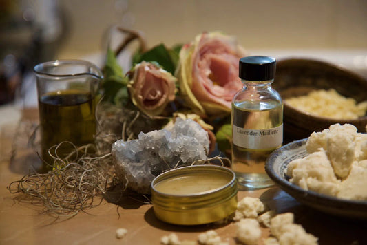 Jarred cosmetic ingredients arranged on a tabletop with a bottle labeled Lavender Maillette and an open balm tin