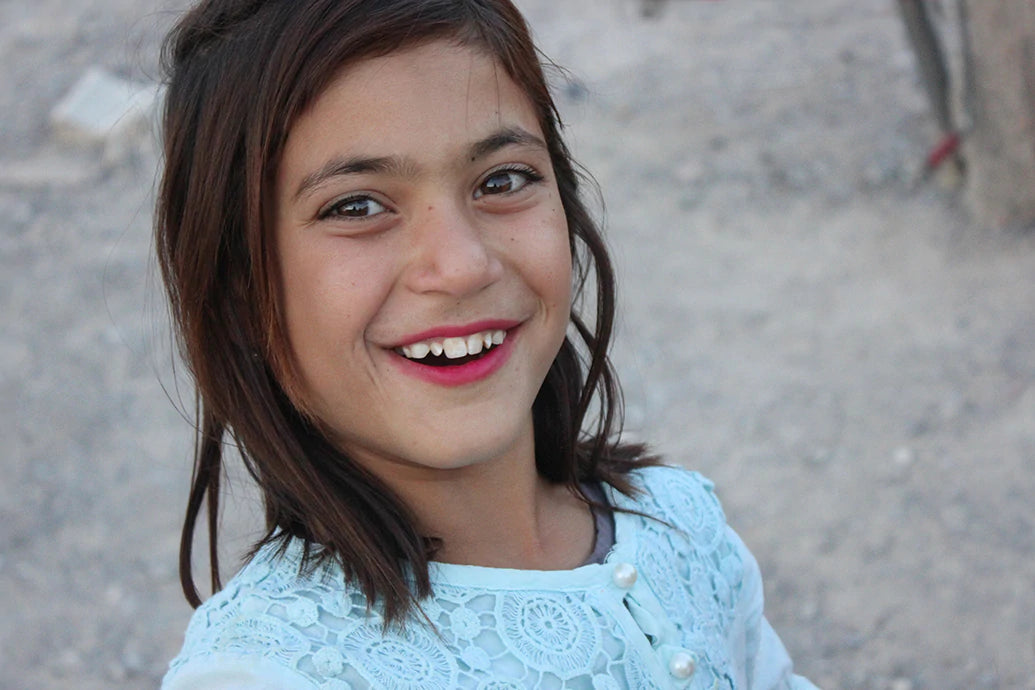 Smiling young girl outdoors wearing a light blue lace top