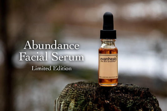 Front view of Abundance Facial Serum amber dropper bottle on a mossy stump, ‘Limited Edition’ text over blurred background
