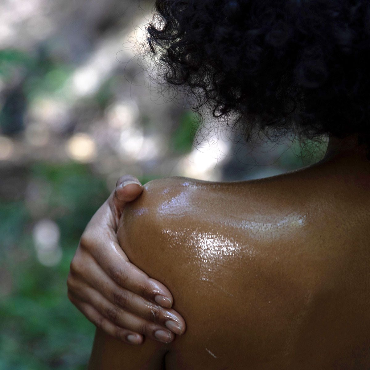 model rubbing shea butter body moisturizer on shoulder