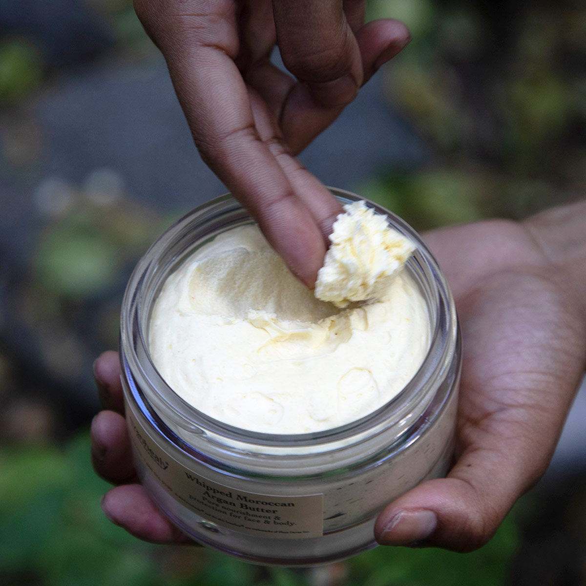 model with shea butter clump on fingertips in nature