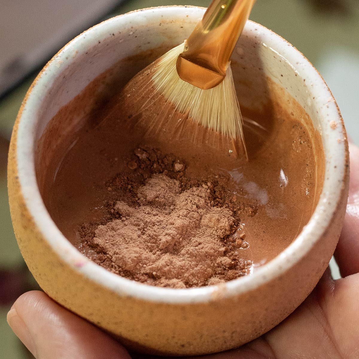 mixing french rose clay mask and hydrosol in handcrafted bowl with fan brush