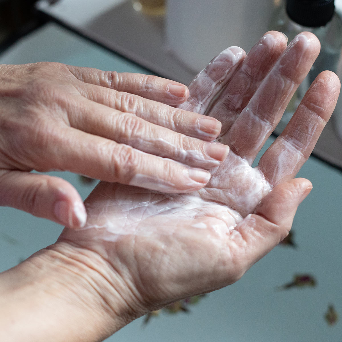 creamy facial cleansing milk cleanser mixed between palm of hands over sink
