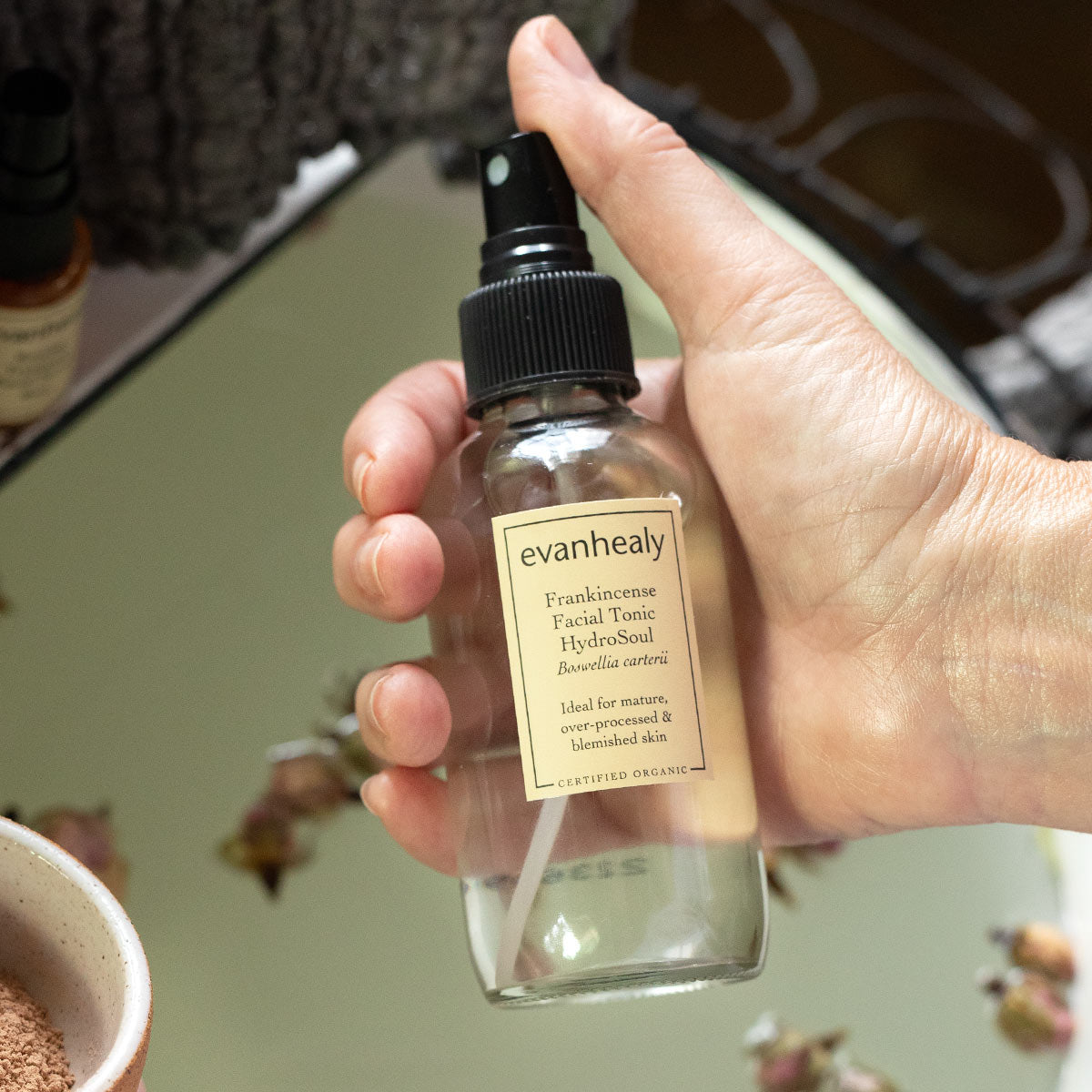 evanhealy frankincense facial tonic hydrosol in hand with thumb on pump