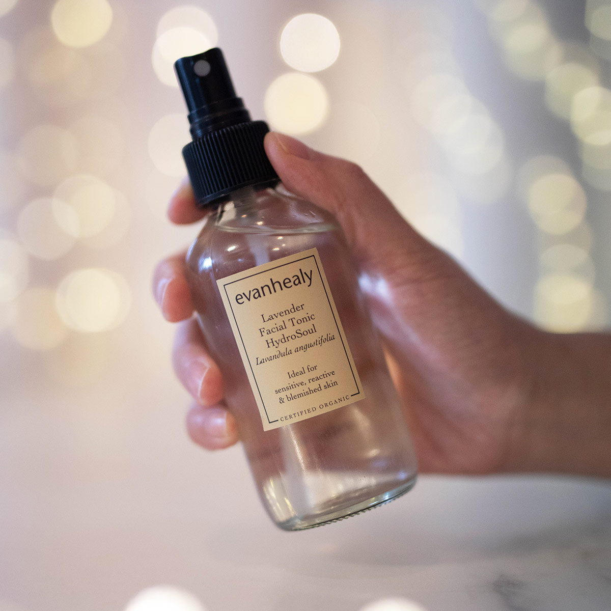 copper distilled lavender hydrosol facial toner in hand with twinkling lights