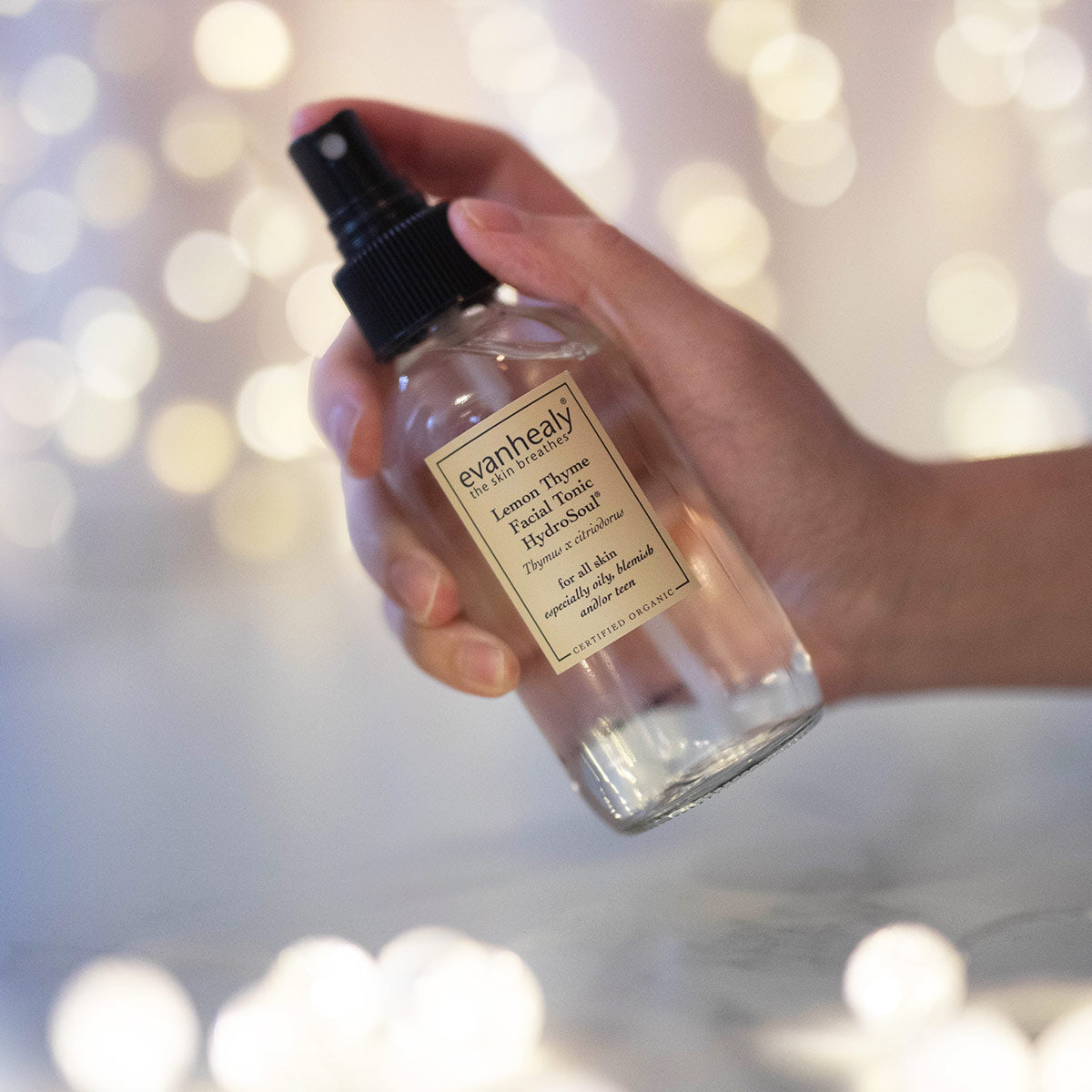 copper distilled lemon thyme hydrosol facial toner in hand with twinkling lights