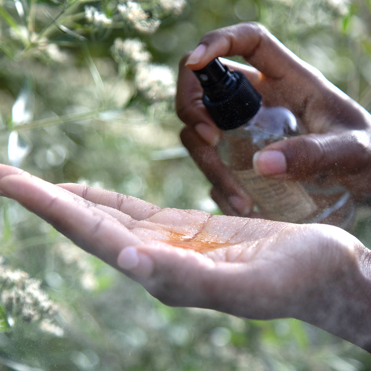 model spraying hydrosol in palm of hand with oil serum
