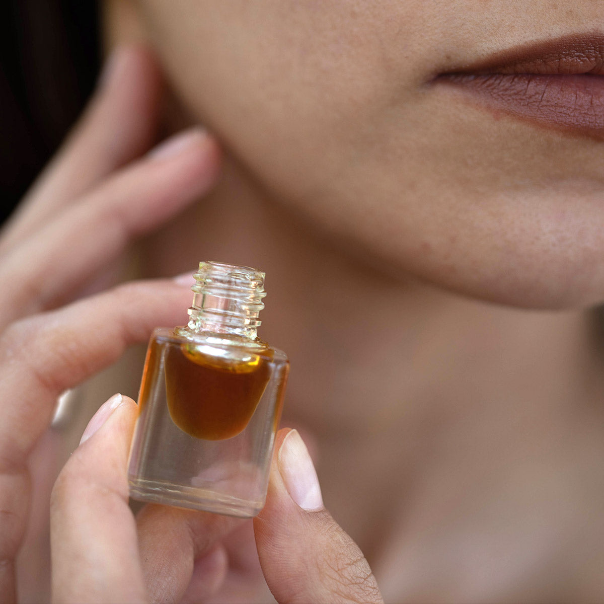 model applying patchouli essential oil perfume to neck