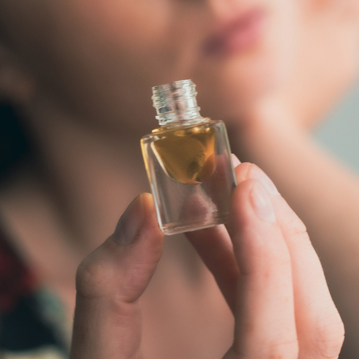 model holding open bottle of jasmine perfume in fingertips