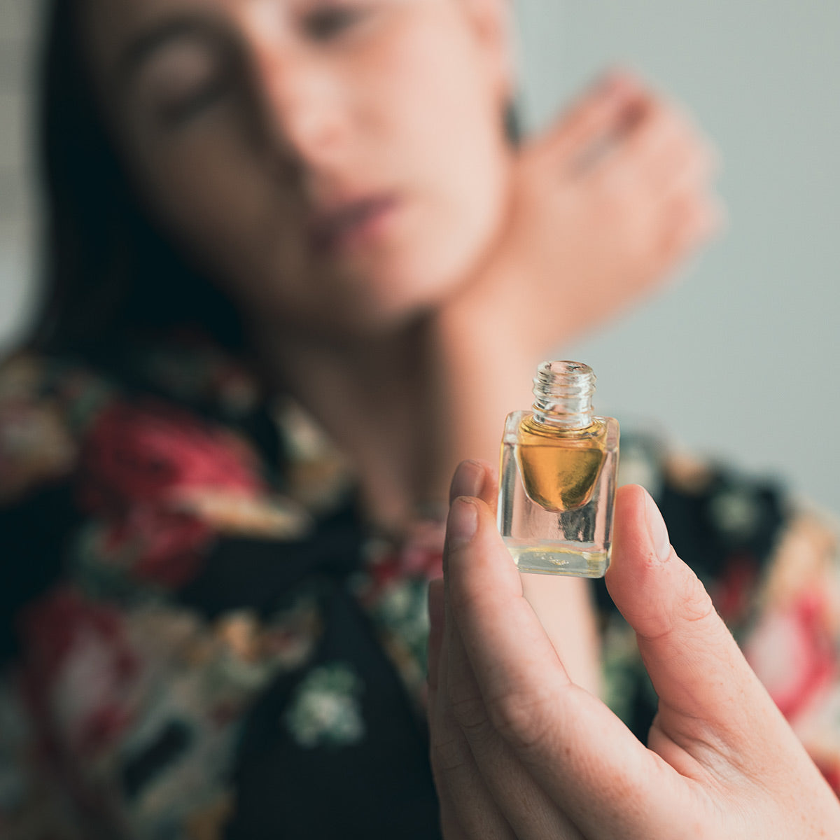 model holding rose otto essential oil perfume in fingertips