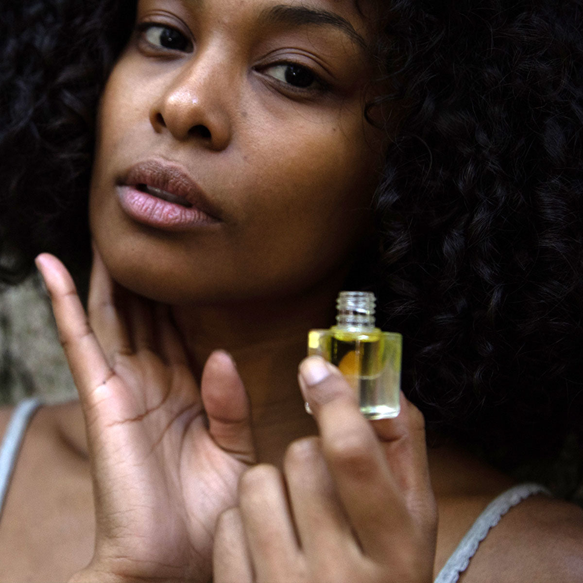 model applying sandalwood essential oil perfume to neck