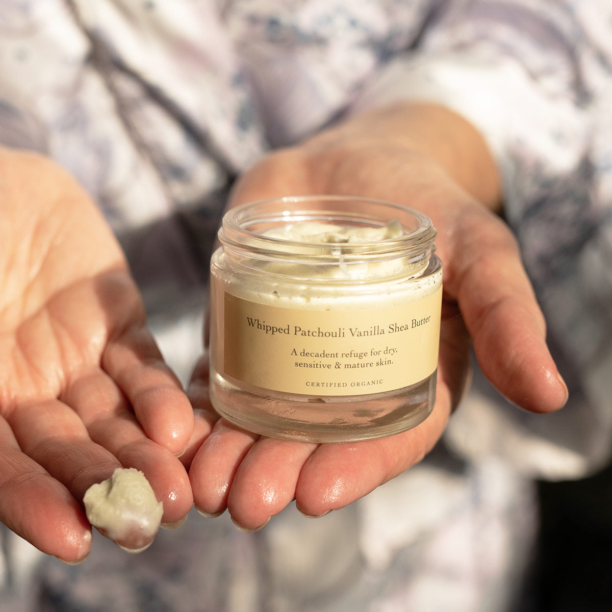 model with whipped patchouli vanilla shea butter on finger showing texture of moisturizer