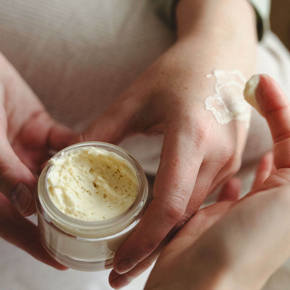 jar of shea butter moisturizer and texture on models hand