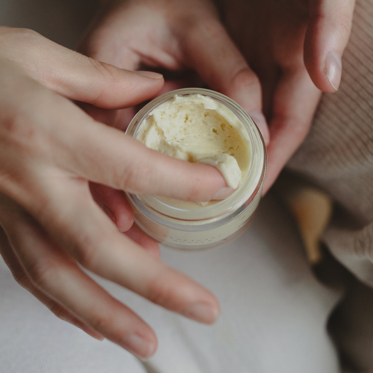 model extracting whipped shea butter with frankincense with fingertip