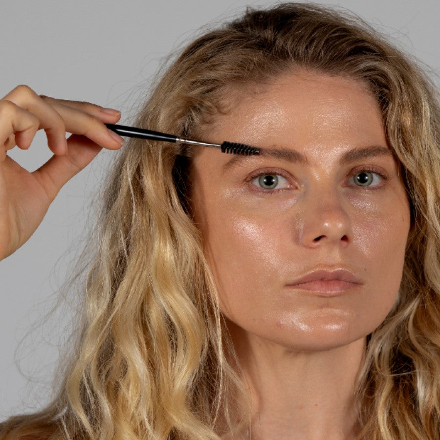 female model applying brow pomade with spoolie brush tip