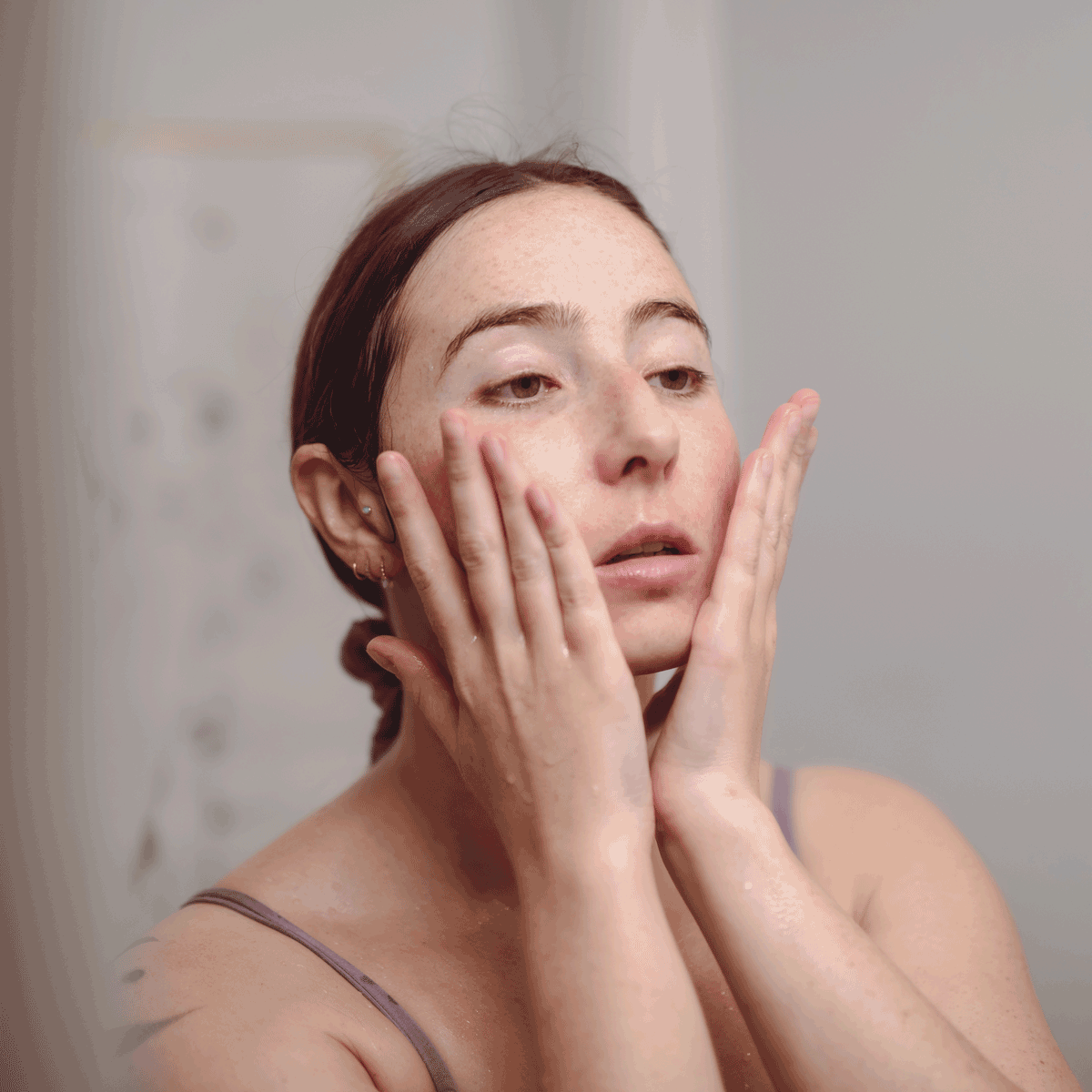 model looking in mirror applying balancing skin care ritual to face